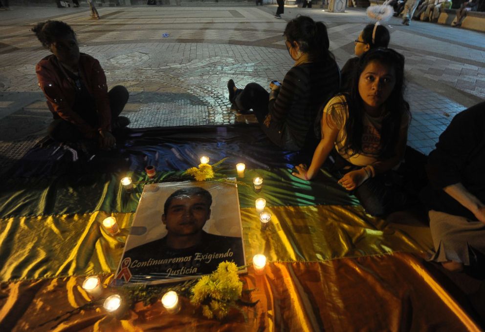 PHOTO: Friends of deceased Honduran political activist and LGBT rights leader Walter Orlando Trochez sit on a gay pride flag with a picture of him during a candlelight vigil in Tegucigalpa, Honduas, Dec. 13, 2012.