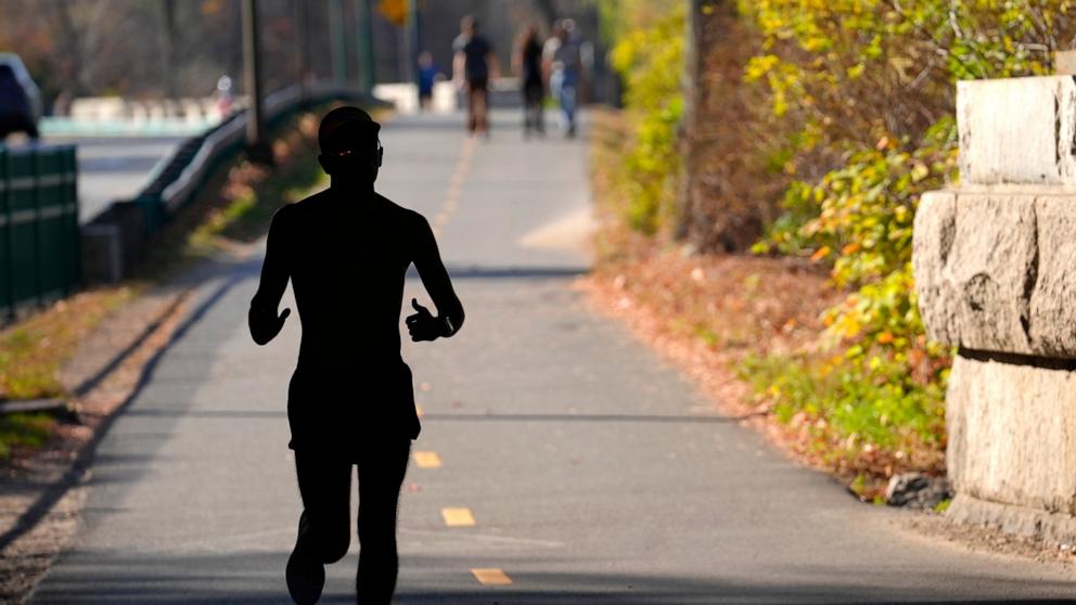 PHOTO: A runner appears in silhouette while running in temperatures in the 70s, Nov. 6, 2024, under a bridge near the Charles River, in Boston.