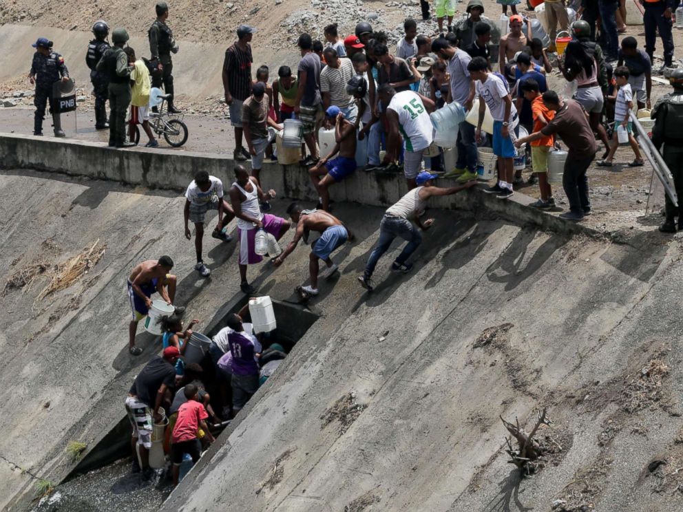 PHOTO: People collect water from a broken pipe, flowing into a sewage canal at the Guaire river in Caracas, Venezuela, March 11, 2019, as a massive power outage continues affecting some areas of the country.
