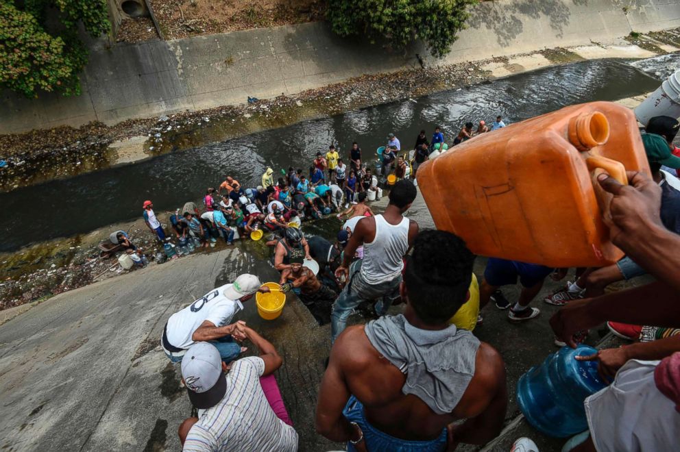 PHOTO: People collect water from a broken pipe, flowing into a sewage canal at the Guaire river in Caracas, Venezuela, March 11, 2019, as a massive power outage continues affecting some areas of the country. 