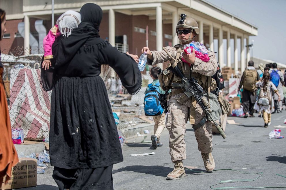 PHOTO: A U.S. Marine provides water to families during an evacuation at Hamid Karzai International Airport, Afghanistan, Aug. 22, 2021.