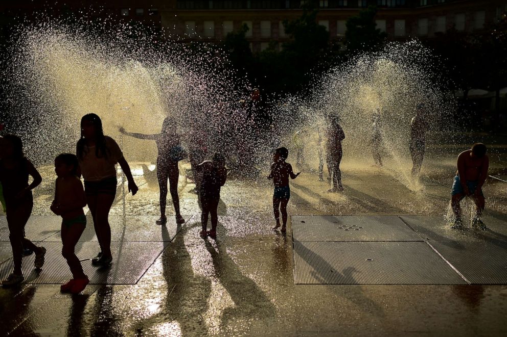 PHOTO: People cool off in a fountain as the sun sets during a hot summer day, in Pamplona, northern Spain,  July, 23, 2019.