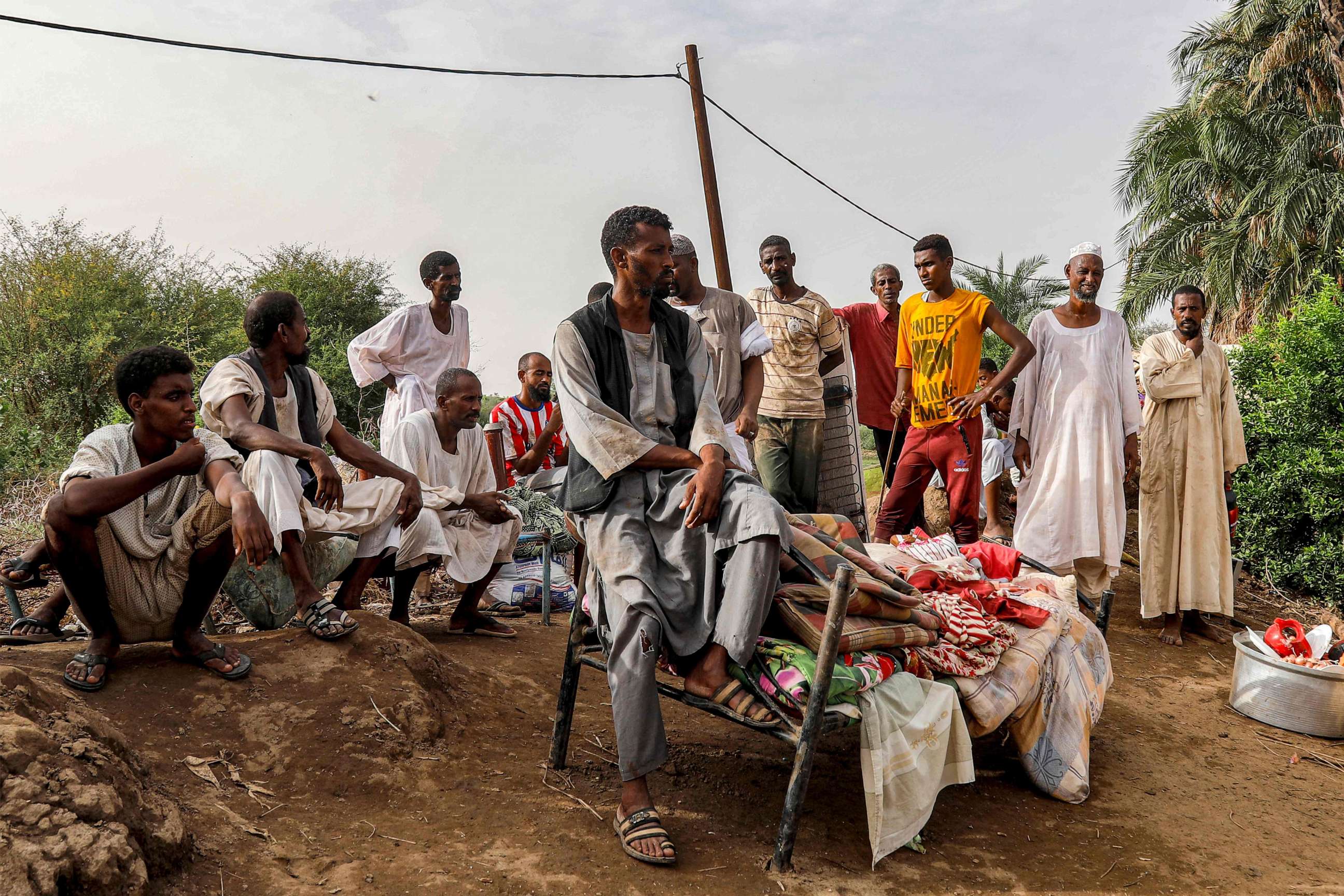 PHOTO: People sit outdoors on salvaged furniture in an area devastated by floods in al-Sagai north of Omdurman on August 6, 2023.