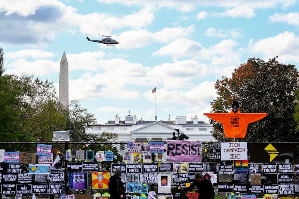 PHOTO: Helicopter passes over the White House, seen behind a fence and protest posters, the day before the U.S. presidential election in Washington, Nov. 2, 2020.