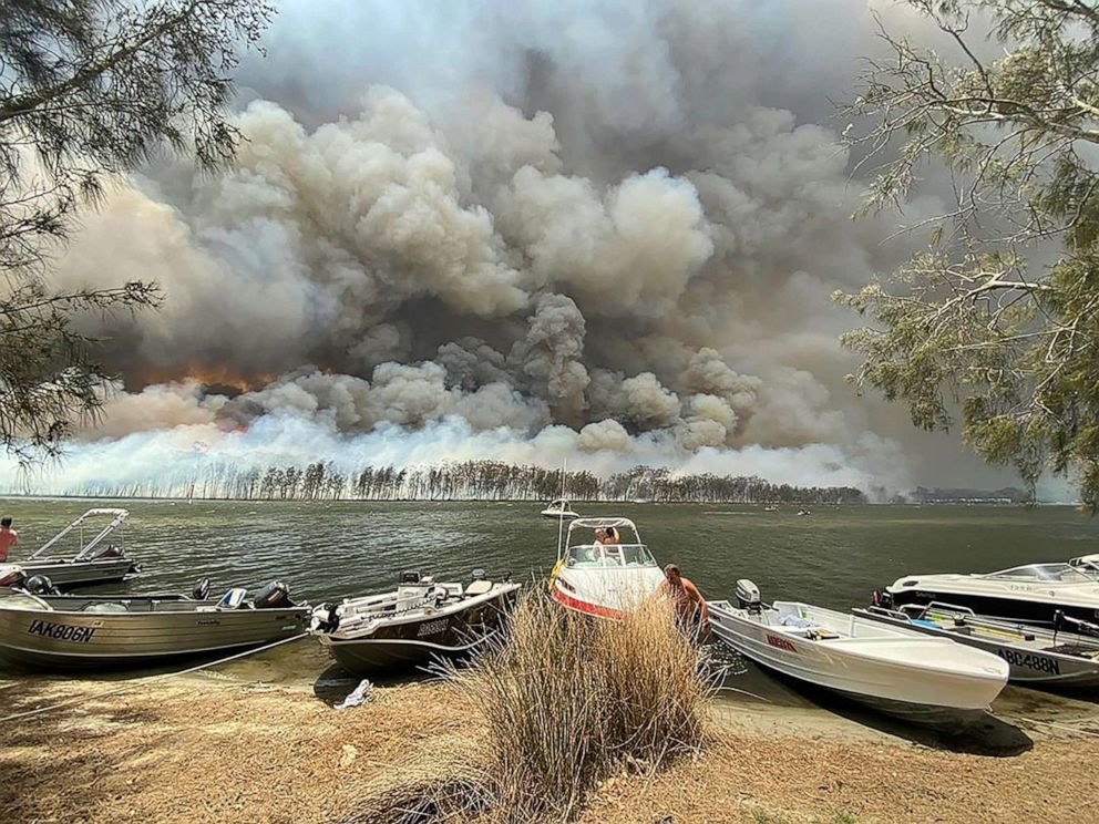 PHOTO: Boats are pulled ashore as smoke and wildfires rage behind Lake Conjola, Australia, Jan. 2, 2020. 