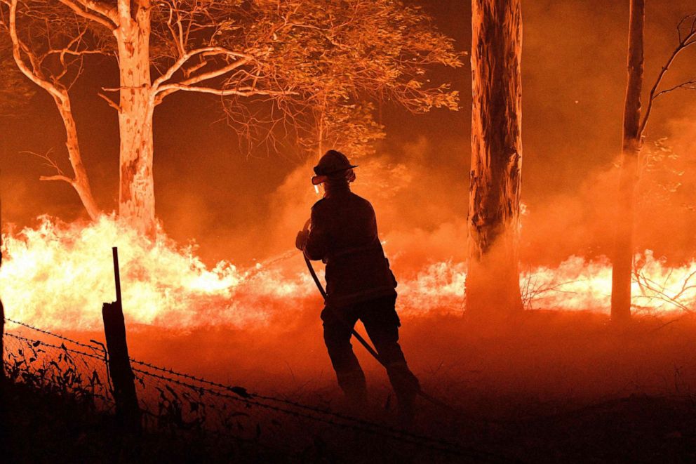 PHOTO: A firefighter hoses down trees and flying embers in an effort to secure nearby houses from bushfires near the town of Nowra in the Australian state of New South Wales, Dec. 31, 2019. 