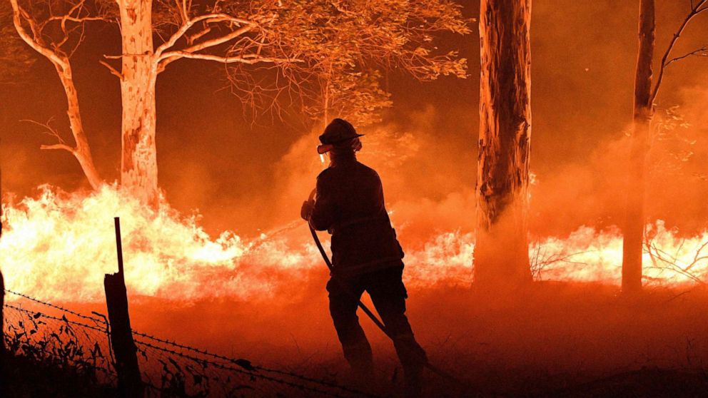 PHOTO: A firefighter hoses down trees and flying embers in an effort to secure nearby houses from bushfires near the town of Nowra in the Australian state of New South Wales, Dec. 31, 2019. 