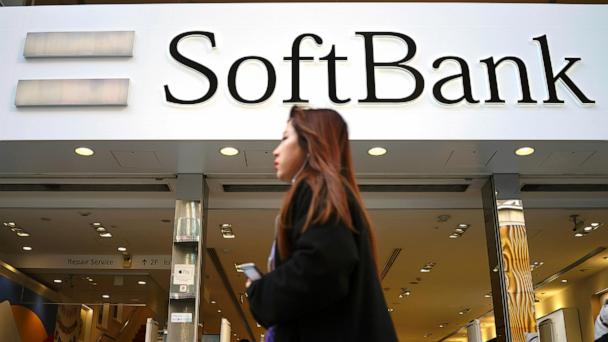 FILE - A woman walks in front of SoftBank store in Ginza shopping district in Tokyo, Jan. 20, 2020. (AP Photo/Eugene Hoshiko, File)