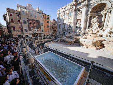 Tourists toss coins over a makeshift pool as Rome’s Trevi Fountain undergoes maintenance