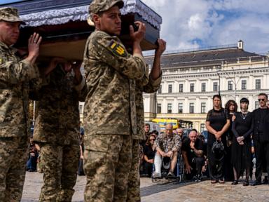 A pregnant soldier mourns her 21-year-old husband at his funeral in Ukraine