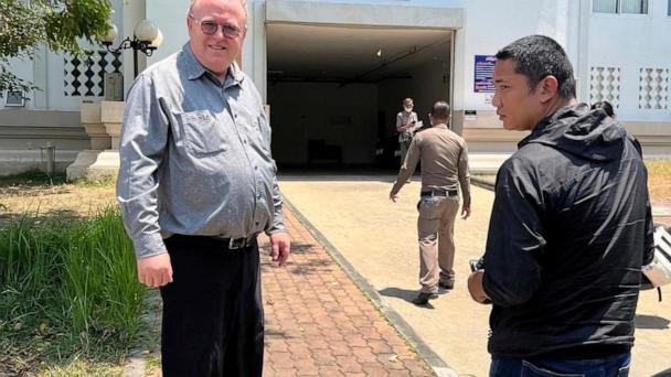 FILE - U.S. political science lecturer Paul Chambers, left, of Thailand's Naresuan University, stands outside the police station in Phitsanulok, Thailand, where he was arrested on charges of insulting the monarchy. (AP Photo, file)