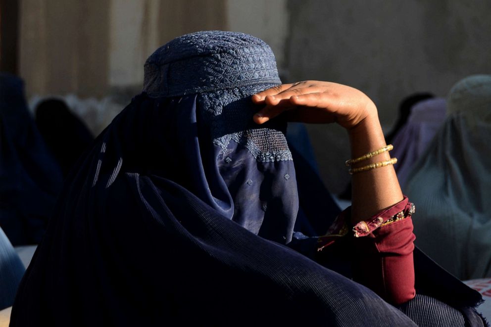 PHOTO: In this March 8, 2022, file photo, a burqa-clad woman waits with others outside a United Nations High Commissioner for Refugees office as they wait to receive non-food items in Kandahar, Afghanistan.