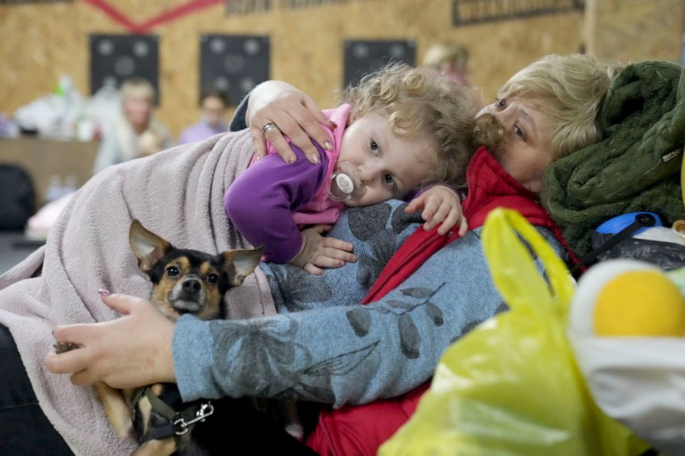PHOTO: A women holds a child and a dog in a shelter inside a building in Mariupol, Ukraine, on Feb. 27, 2022. 