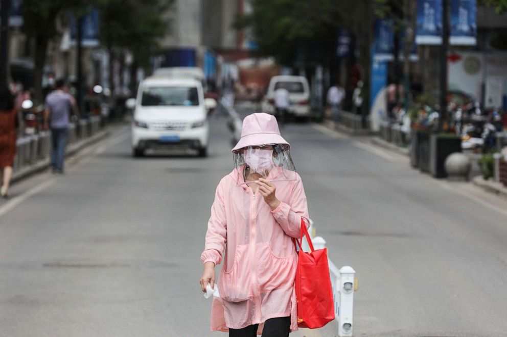 PHOTO: A woman wears a face shield as she walks along a street in Wuhan in China's central Hubei province on May 11, 2020.