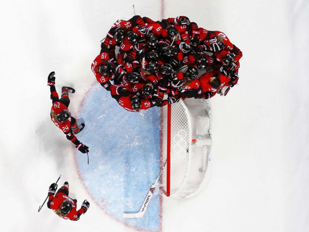 PHOTO: Team Canada players mob goalkeeper Genevieve Lacasse after defeating Team USA in the womens preliminary round match, Feb. 15, 2018, in Pyeongchang, South Korea.