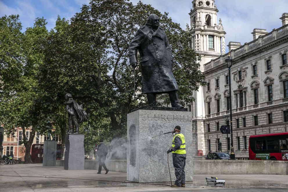 PHOTO: A worker cleans the statue of Winston Churchill in Parliament Square in London on June 8, 2020, after it had been spray-painted with the words "was a racist" during protests over the weekend.