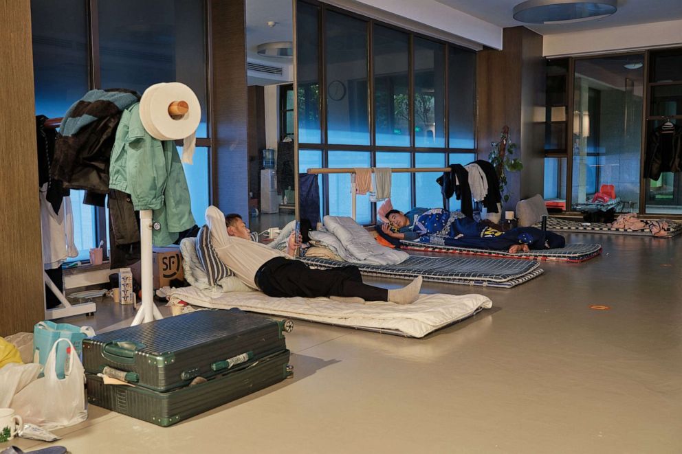 PHOTO: Community workers browse their mobile phone on temporary beds at a gym in a compound during a Covid-19 lockdown in Pudong district in Shanghai, April 13, 2022.