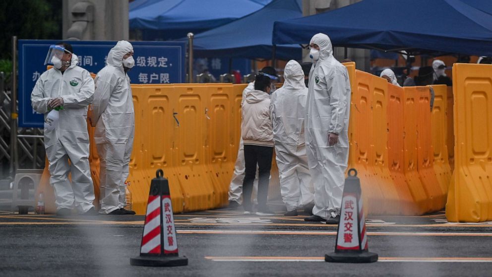 PHOTO: People wearing protective suits as a preventive measure against the COVID-19 coronavirus control an access point to the Biandanshan cemetery in Wuhan in China's central Hubei province, March 31, 2020.