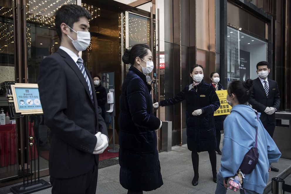 PHOTO: Staff members wearing face masks are seen at an entrance of a Wuhan business plaza, March 30, 2020 in Hubei Province, China. 