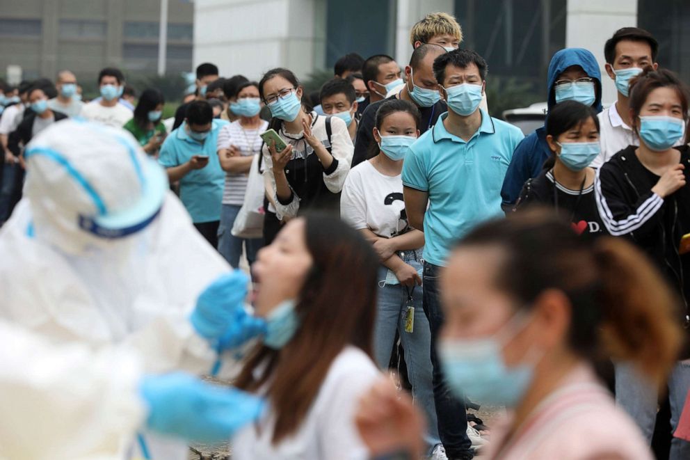 PHOTO: People line up for medical workers to take swabs for the COVID-19 test at a large factory in Wuhan in central China's Hubei province on May 15, 2020.