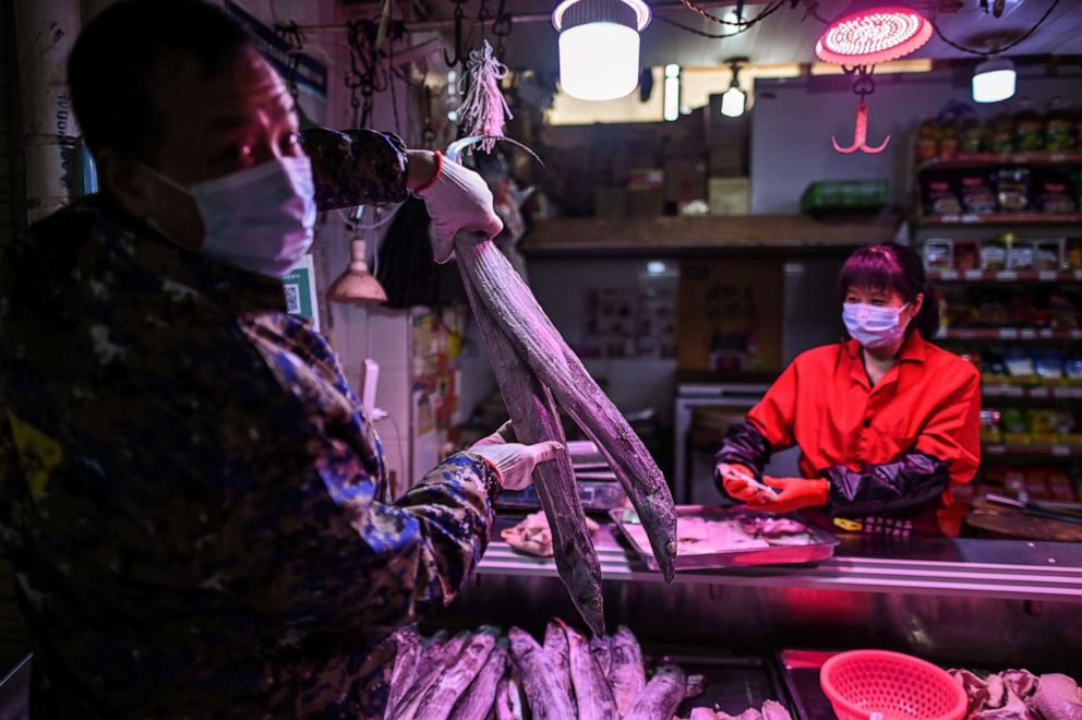 PHOTO: A man wearing a face mask holds a fish in a market in Wuhan, in China's central Hubei province on April 7, 2020.