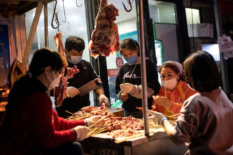 PHOTO: Workers wearing facemasks make a barbecue at a market in Wuhan, in China's central Hubei province on April 4, 2020.