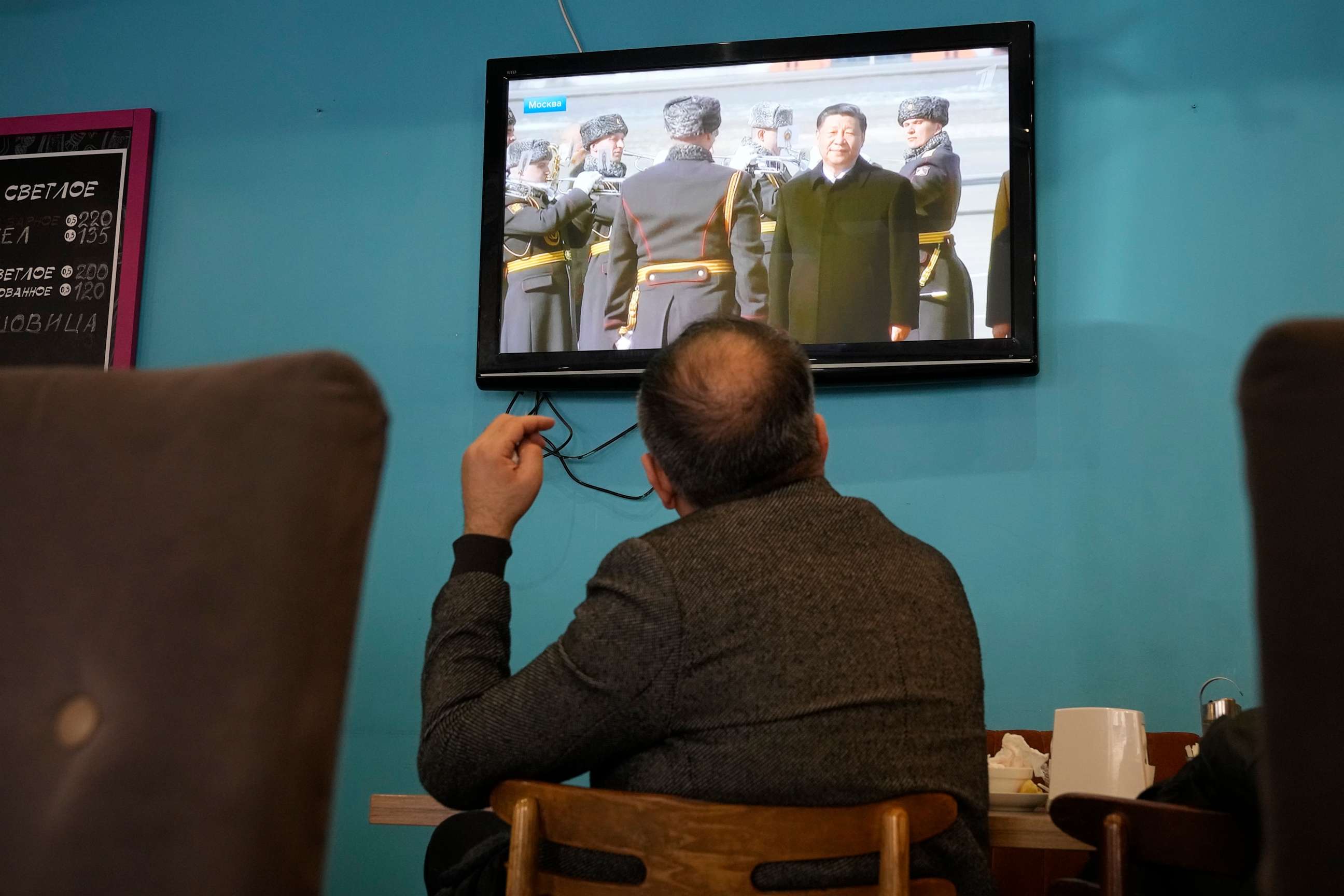 PHOTO: A TV screen displays Chinese President Xi Jinping attending an official welcome ceremony upon his arrival at the Vnukovo-2 government airport outside Moscow, in a cafe in St. Petersburg, Russia, Monday, March 20, 2023.