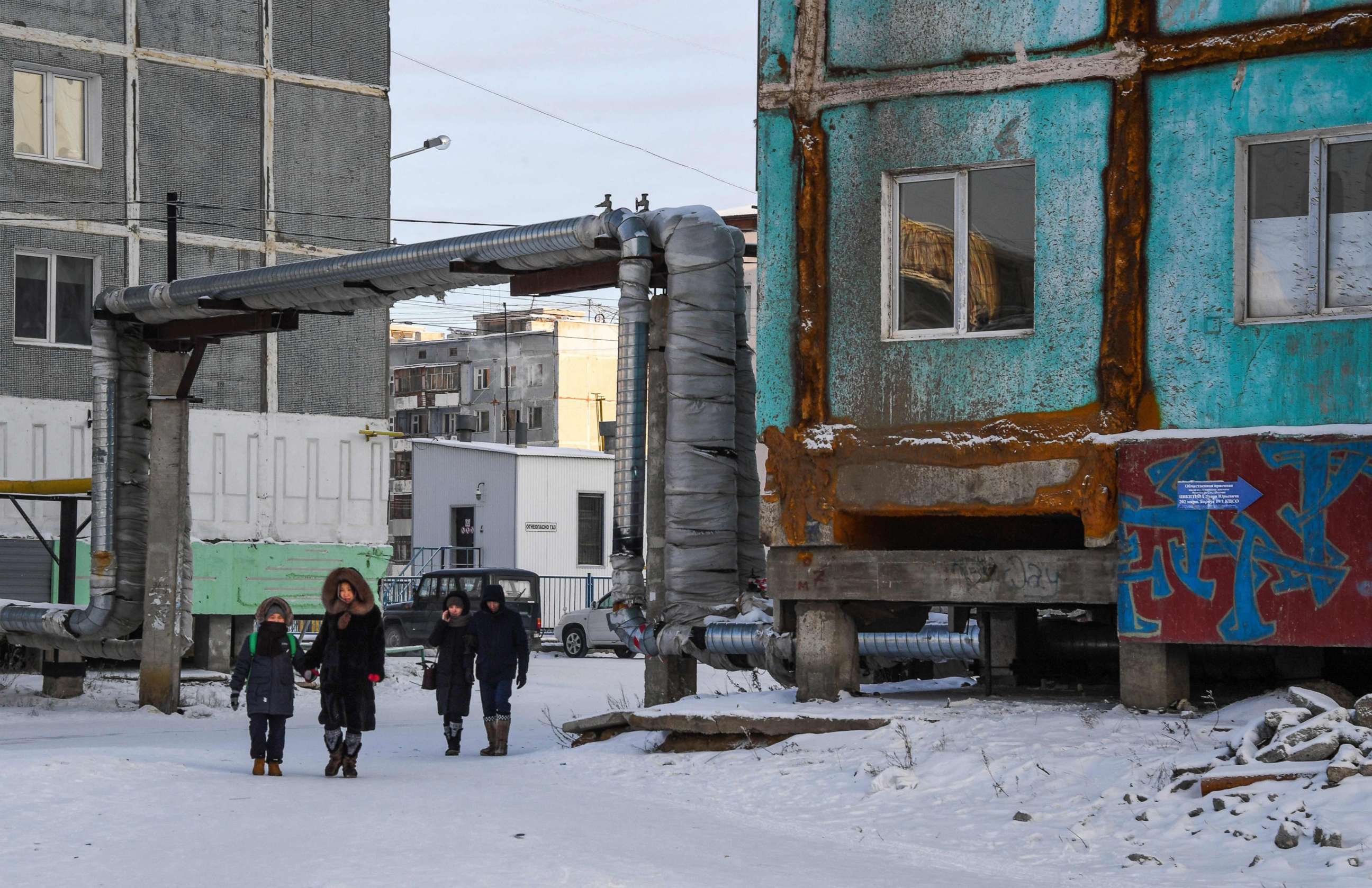 PHOTO: People walk next to a cracked panel apartment building in the eastern Siberian city of Yakutsk, Nov. 26, 2018.