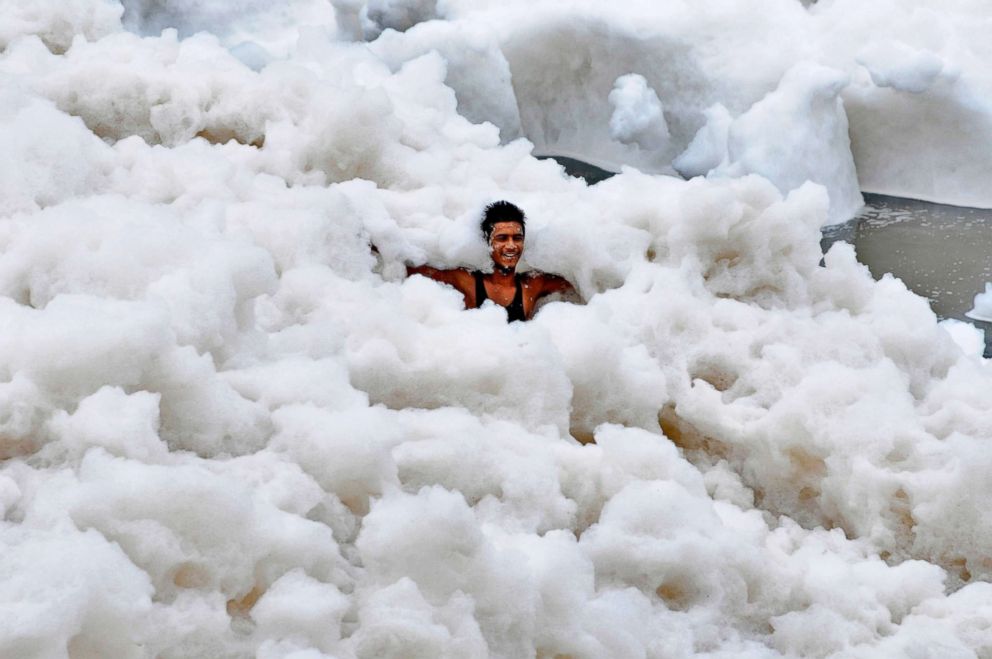 A man immerses himself in a large amount of toxic foam formed along the banks of the Yamuna on July 12, 2015, in Noida, India. The pollution is caused in part to high ammonia levels emanating from the high discharge of industrial pollutants in the river. 