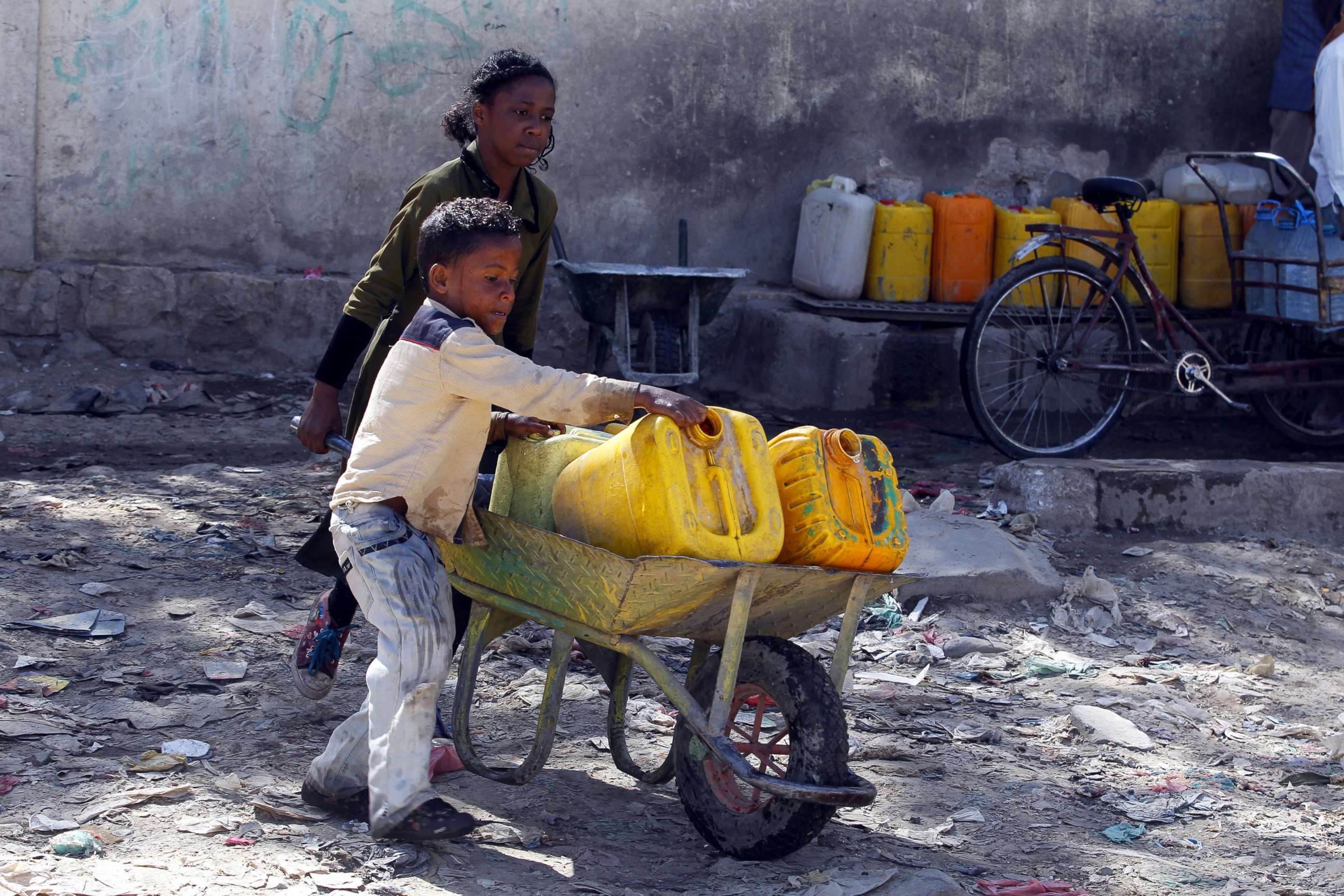 PHOTO: Yemeni children push a wheelbarrow with jerrycans filled with drinking water from a donated water pipe in Sana'a, Yemen, Nov. 18, 2017. 