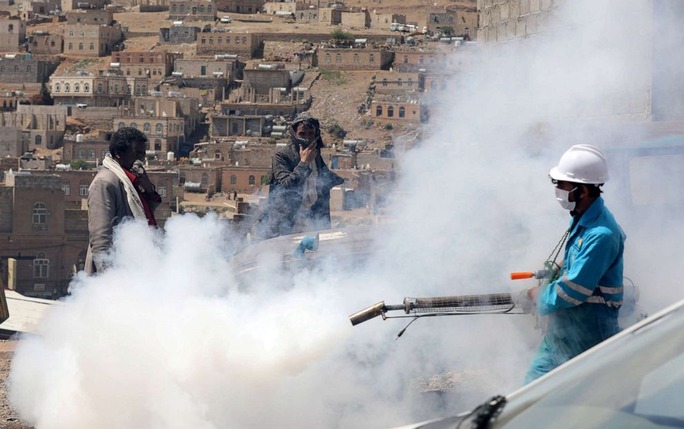 PHOTO: People cover their faces as a health worker fumigates a residential area in the battle against the coronavirus outbreak on the outskirts of Sanaa, Yemen, April 13, 2020.