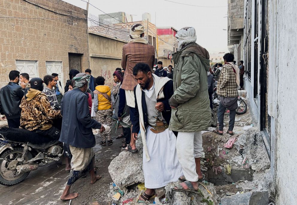 PHOTO: People stand outside a school at the site of a stampede, in Sanaa, Yemen, April 20, 2023.