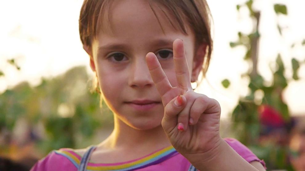 A young girl flashes a v-sign for peace during the funeral.