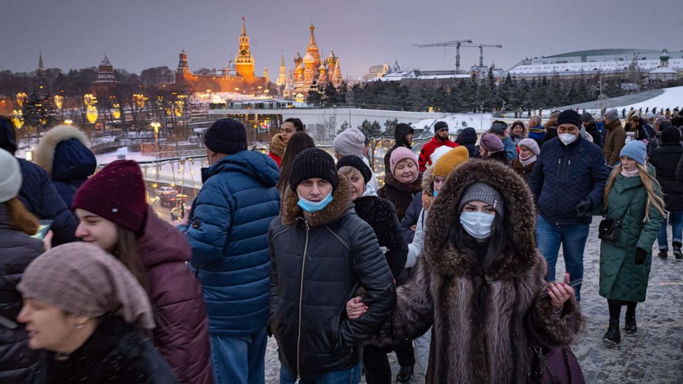 PHOTO: People, with just some wearing face masks to protect against the novel coronavirus, walk on a bridge in Zaryadye Park, with the Kremlin and St. Basil's Cathedral in the background decorated for the holidays, in Moscow, Russia, on Jan. 4, 2021.