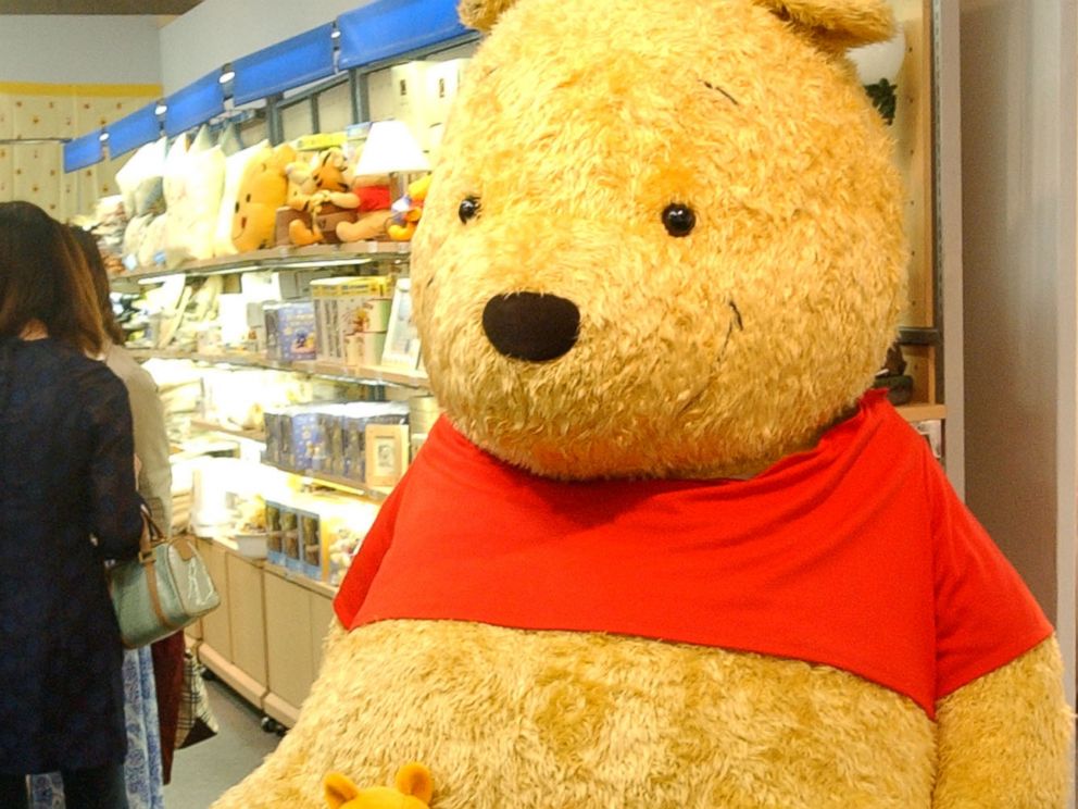 Two boys chat in front of a giant stuffed doll of Winnie-The-Pooh at the World of Winnie-The-Pooh exhibition at a Tokyo department store in this April 24, 2002 photo.
