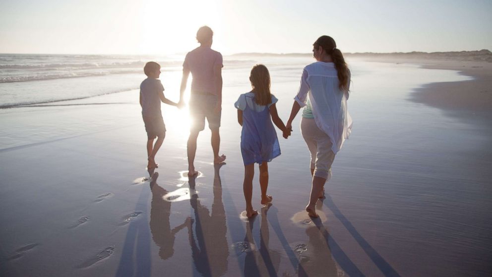 A family walking together on a beach at sunset in this undated photo.