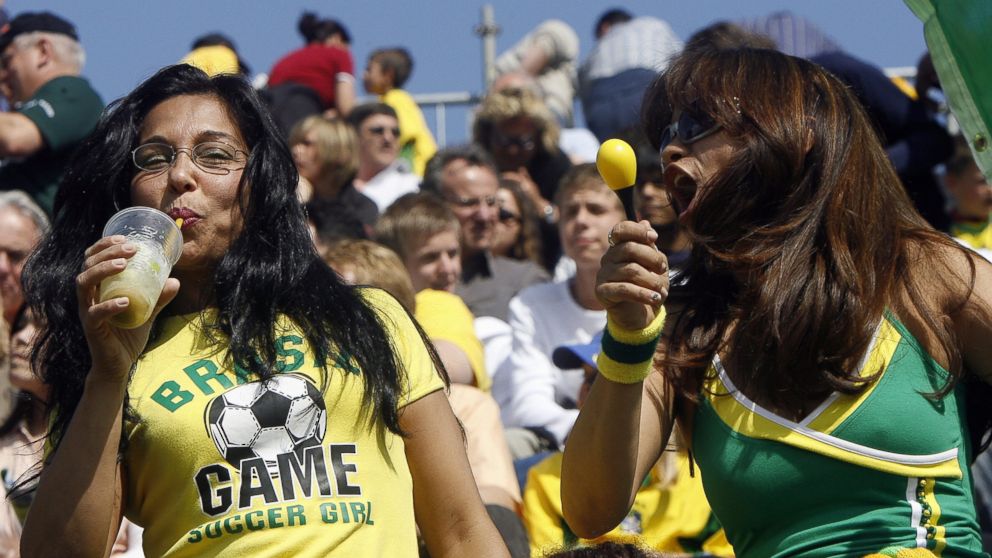 A Brazilian football fan enjoys a Caipirinha while singing samba with another fan as the team starts its first training session in Weggis, Switzerland, May 24, 2006. 