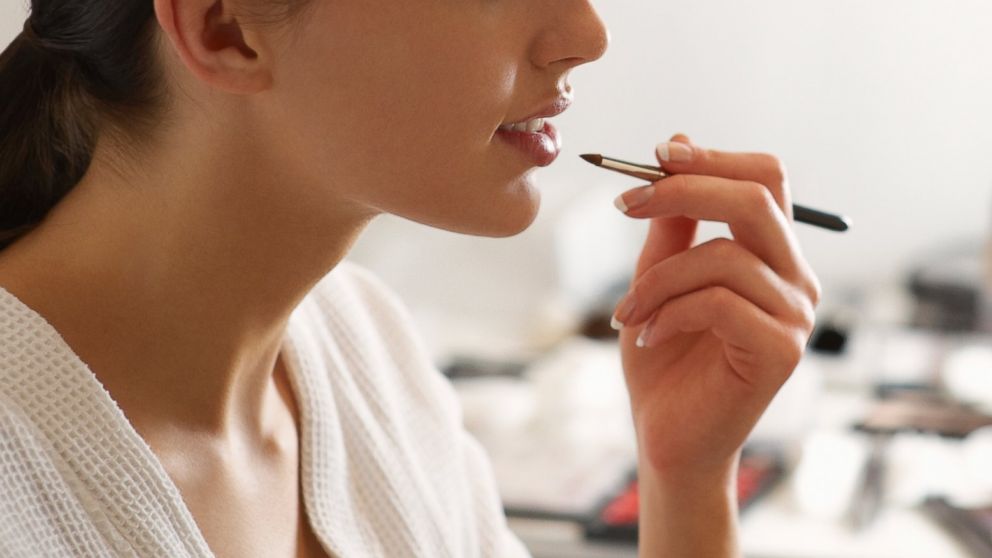 A woman is applying makeup in this stock image.