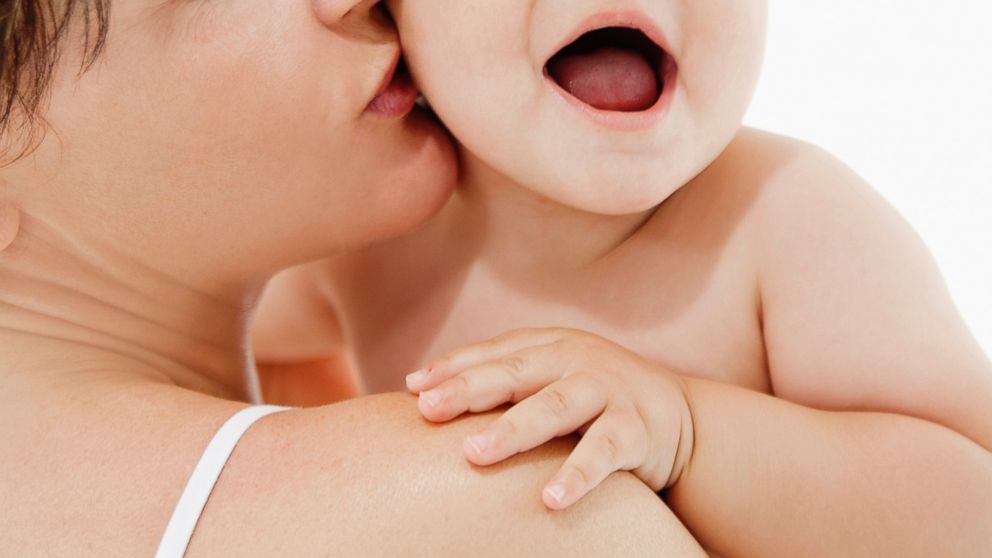 A mother is pictured kissing a baby boy in this stock image. 