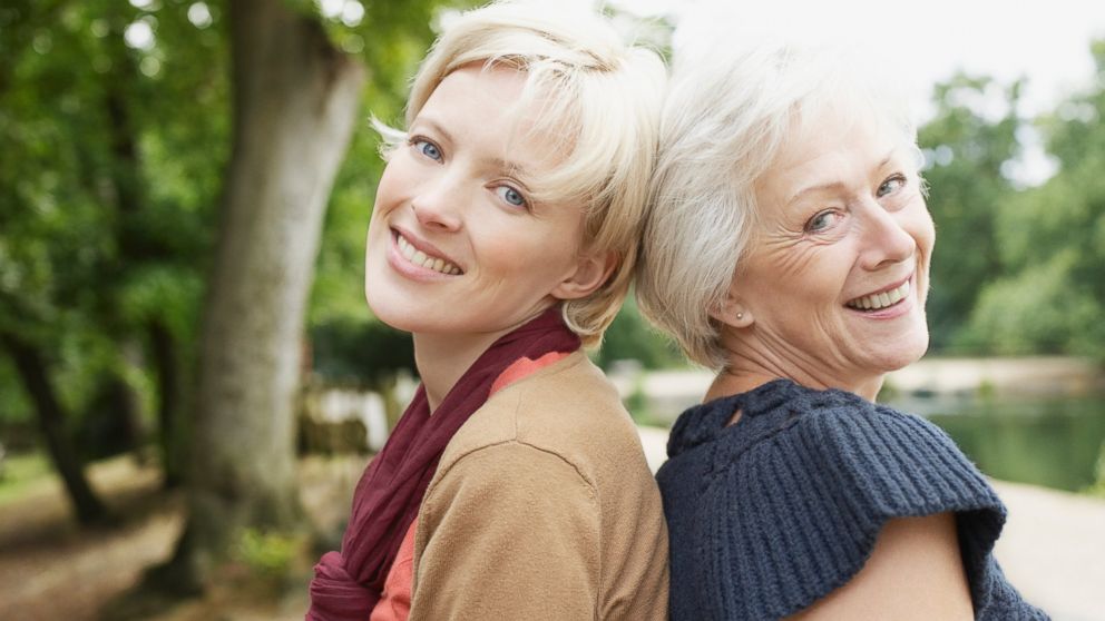 A senior mother and her daughter are pictured near a pond in this stock photo. 
