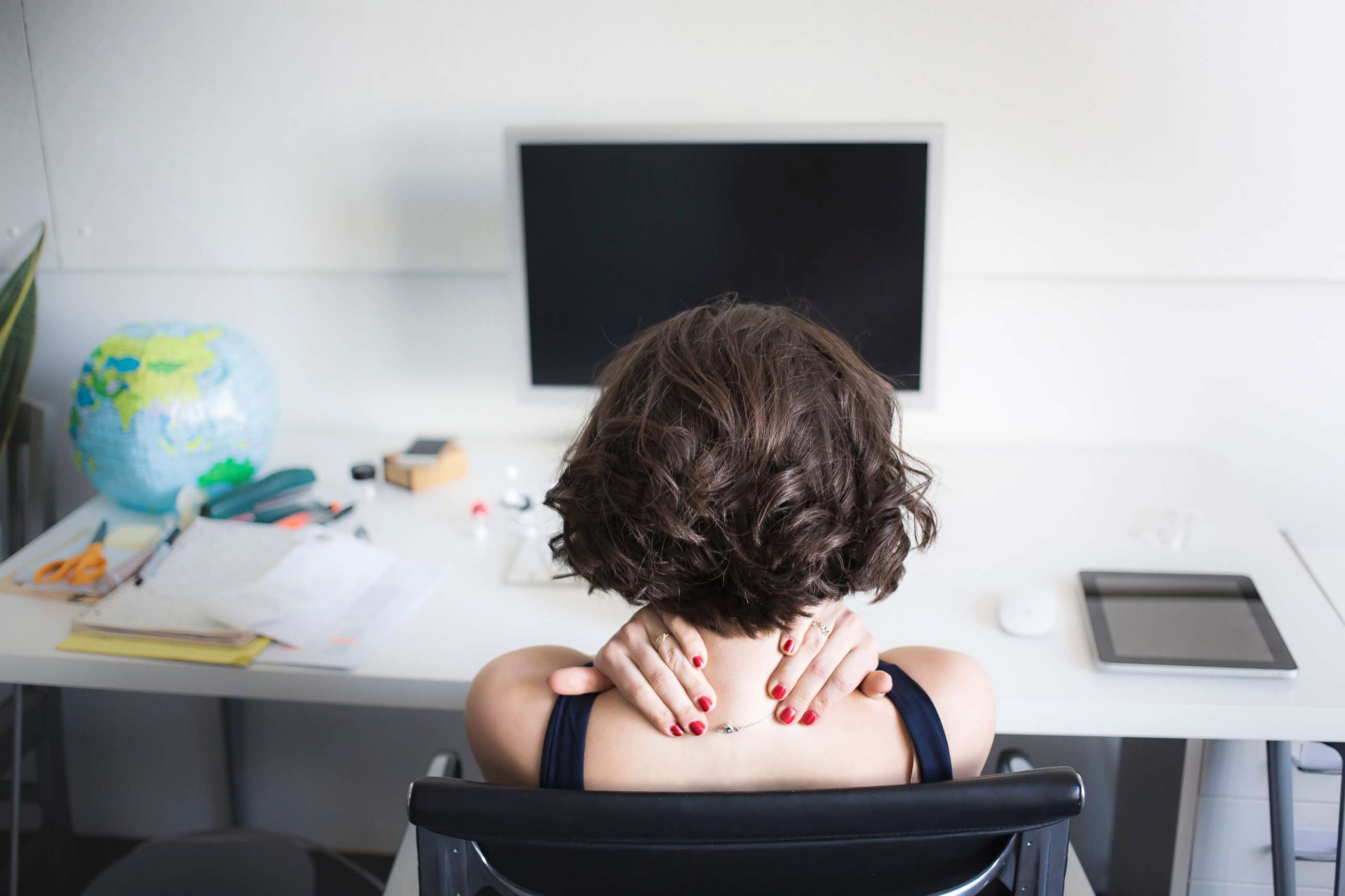 PHOTO: A young woman massages her neck at a desk in an undated stock photo.