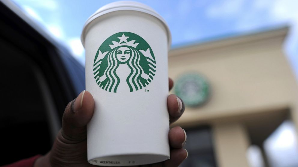 A woman holds up her cup in front of a Starbucks coffee shop in Silver Spring, Md., March 28. 2013.