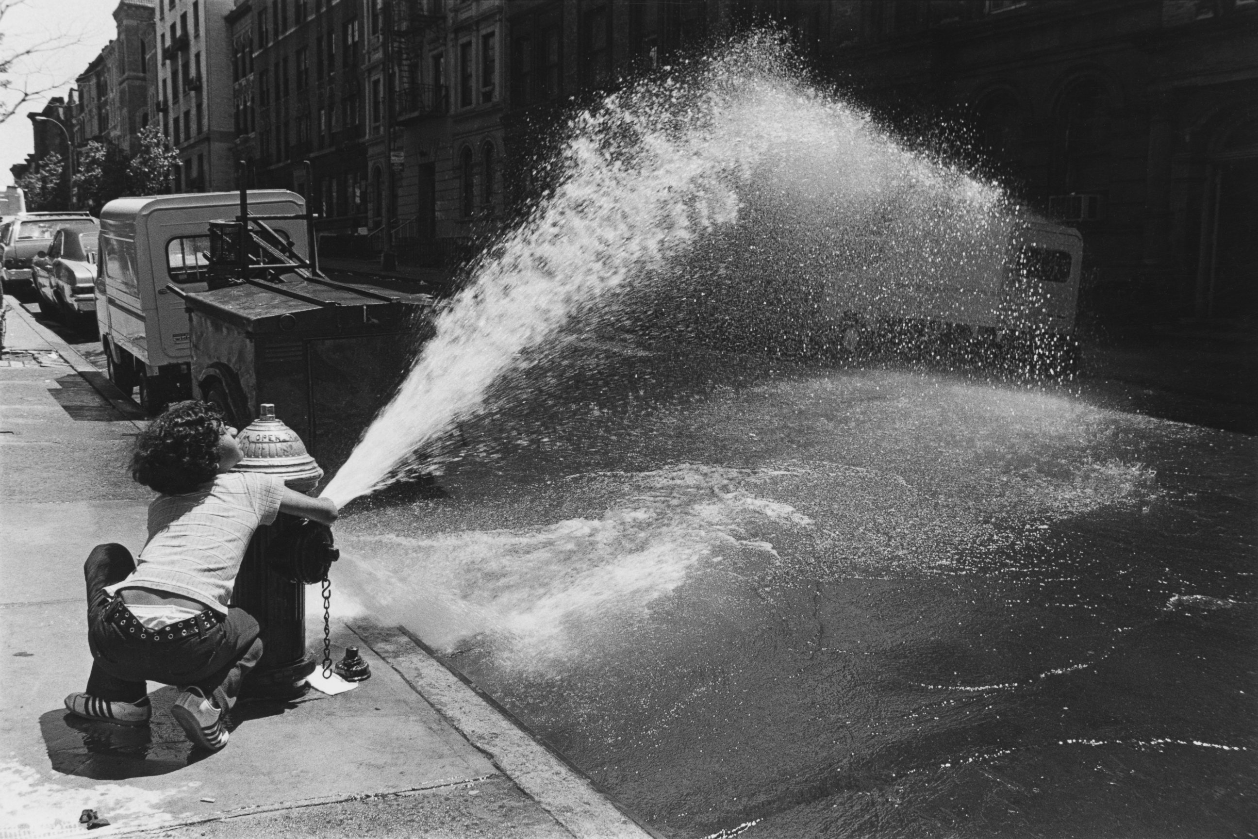 PHOTO: A boy grabs onto a fire hydrant spraying water onto a street in New York, June 12, 1976.
