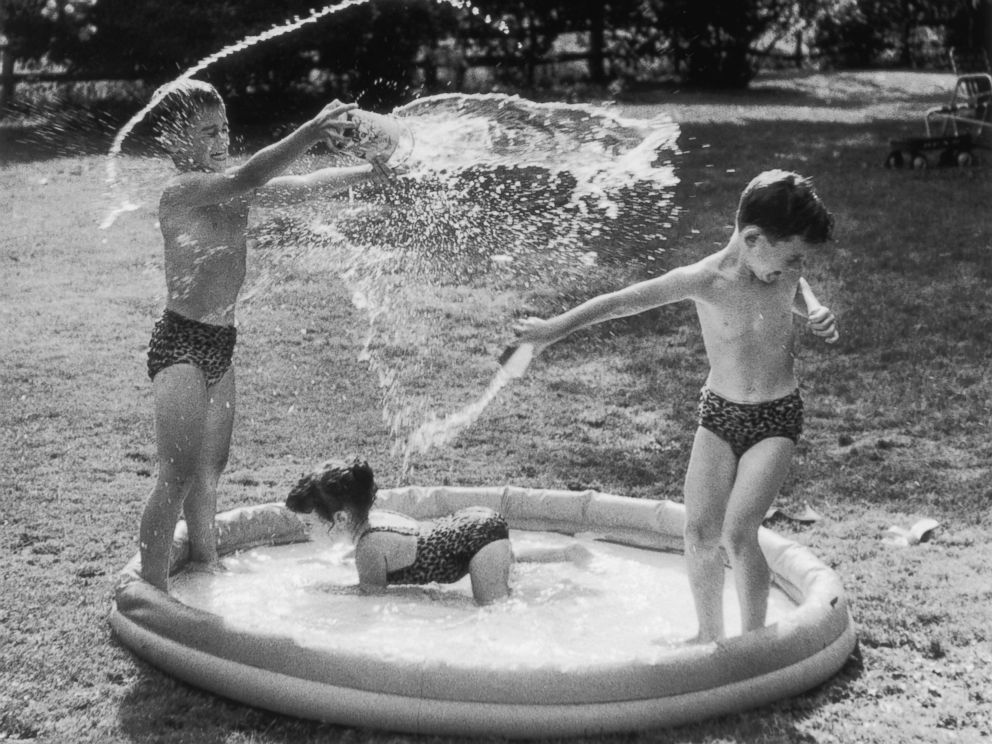 PHOTO: Three children in leopardskin swimsuits splash around in a swimming pool, circa 1950.