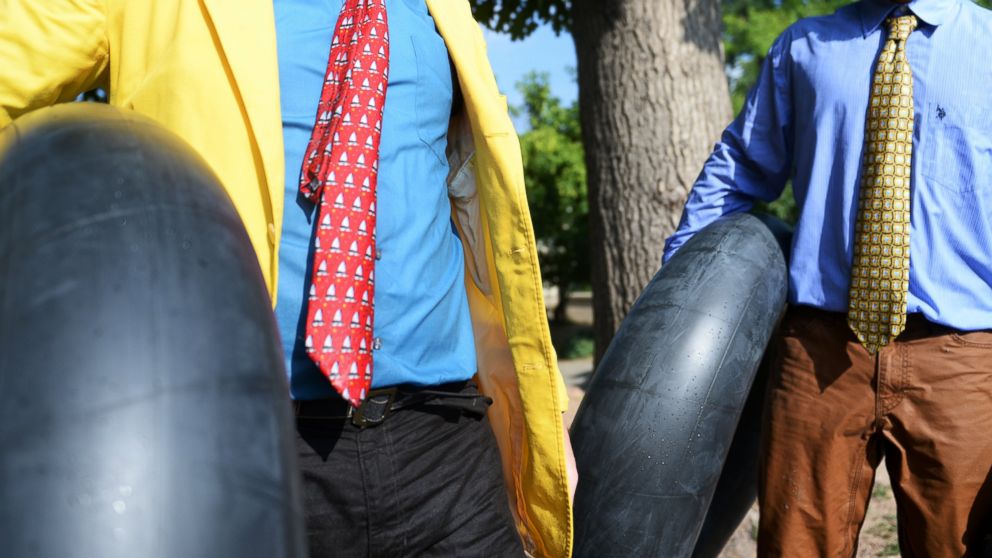 Tim Laramy, left, and Jack Craig dressed in ties carry their tubes as they finish riding Boulder Creek during Boulder's Tube to Work Day, July 15, 2014. 