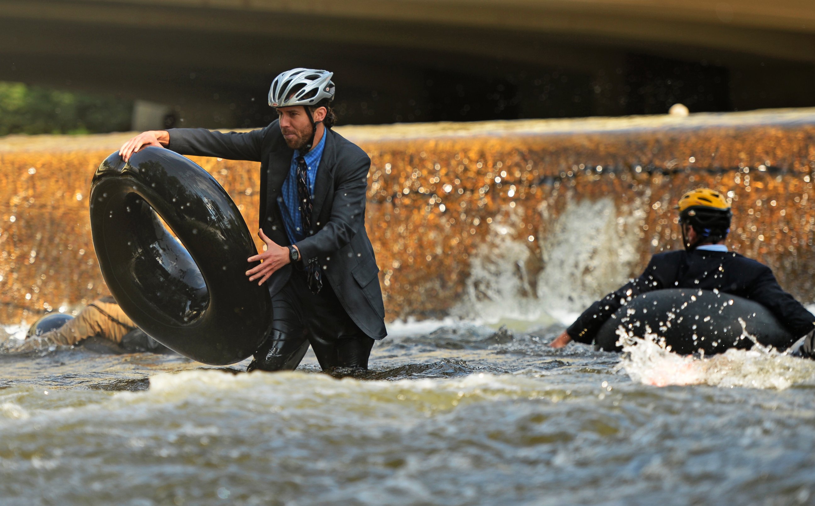 PHOTO: Quayle Hodek, dressed in a suit and tie, hops back on his tube during Boulder's Tube to Work Day, July 15, 2014. 