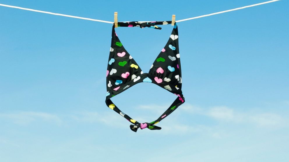 A bikini top hangs on a clothesline.