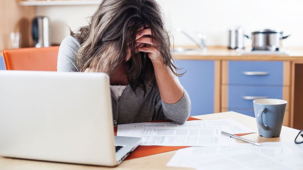 A woman holds her head in front of her laptop at her desk in this undated stock photo.