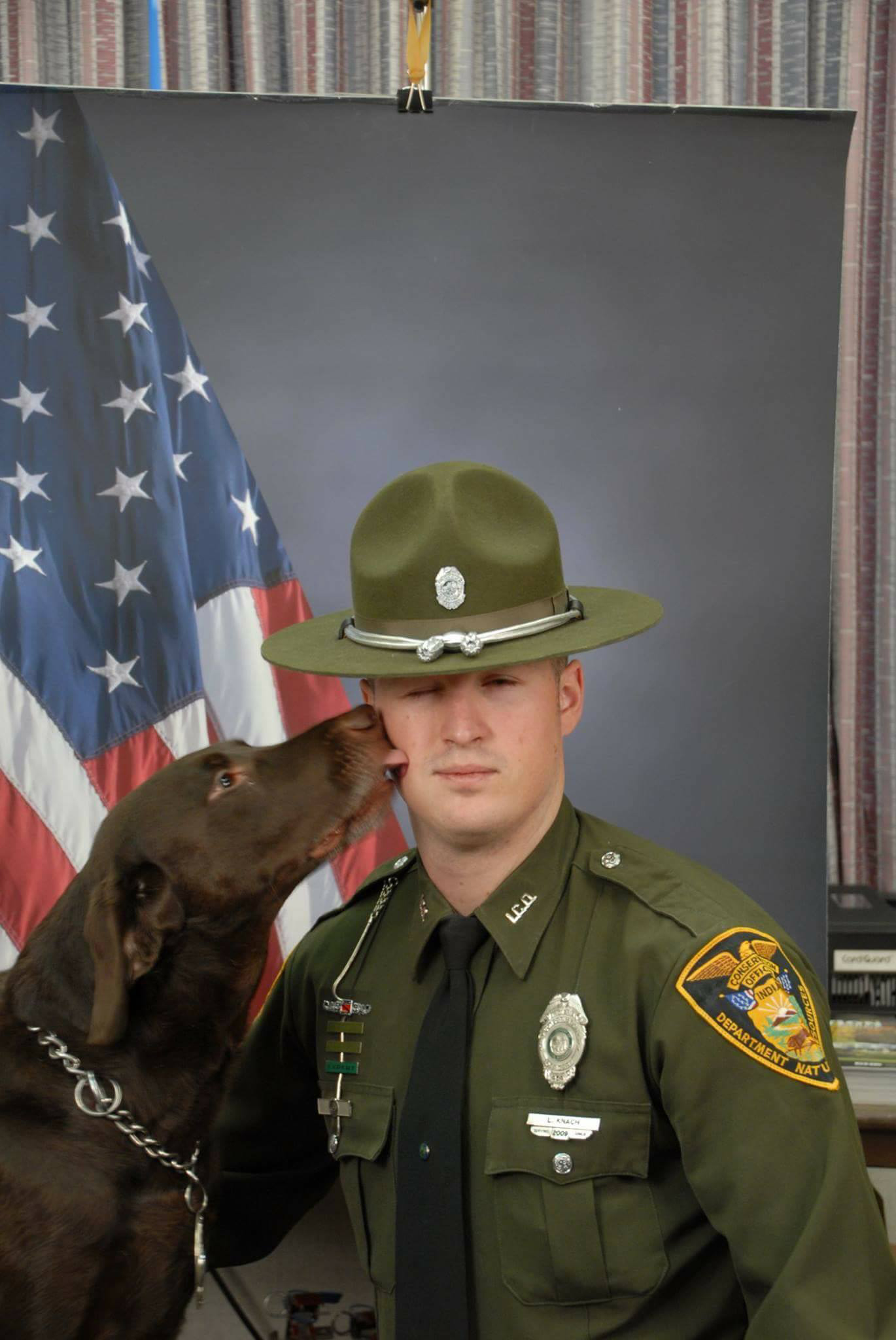 PHOTO: Indiana Conservation Officer Levi Knach's K-9 dog partner wouldn't stop licking his face during his work portraits. 