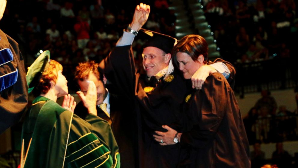 PHOTO: Sam Bridgman stood up with the help of two friends and physical trainers to walk across the graduation stage at USF, May 7, 2017.